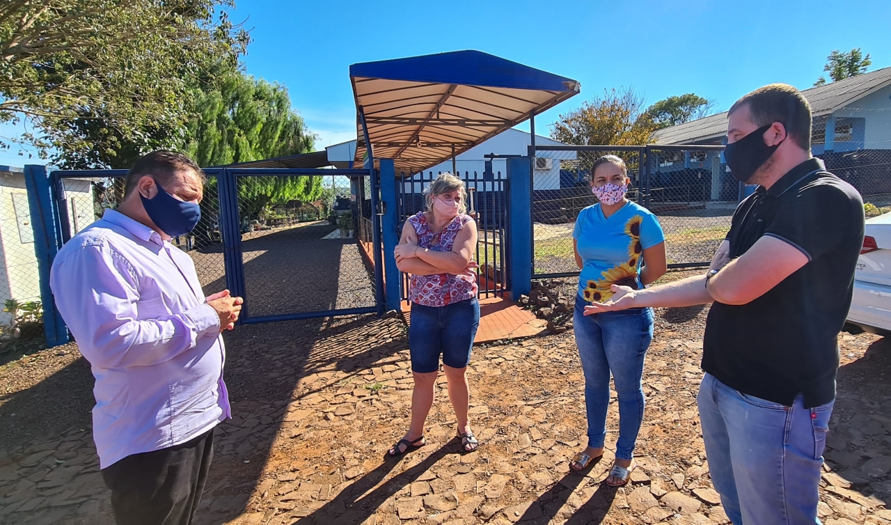 Melo (esq.) e o engenheiro Juliano conversam na frente da escola com as diretoras